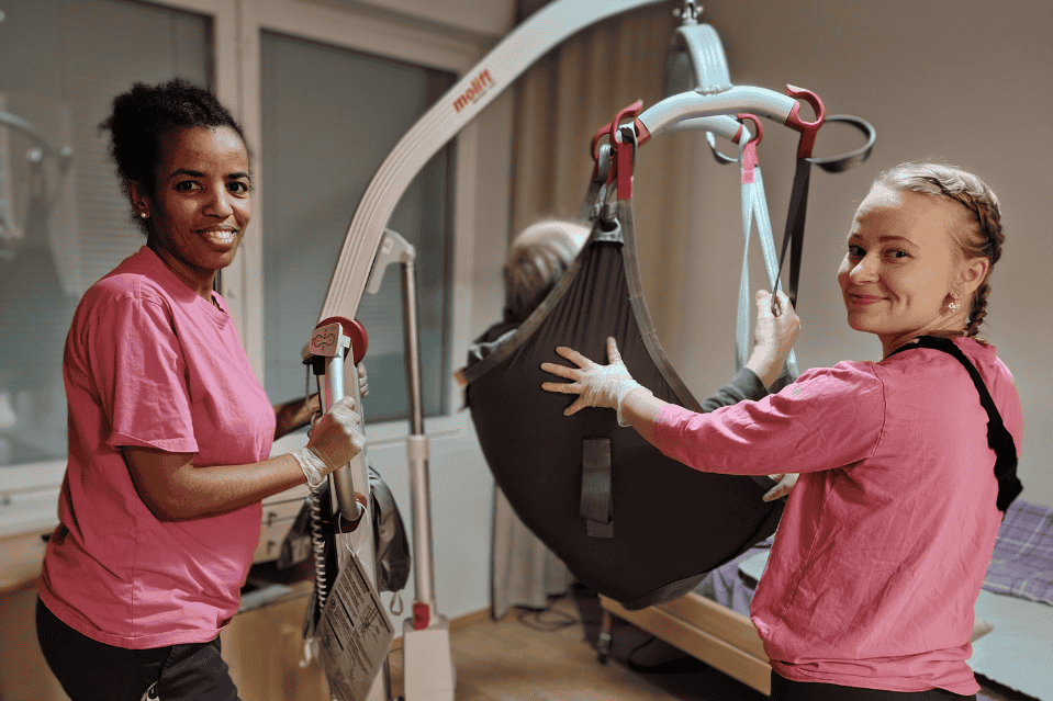 Kaksi hoitajaa käyttää nostotuolia yhdessä hoivakodissa